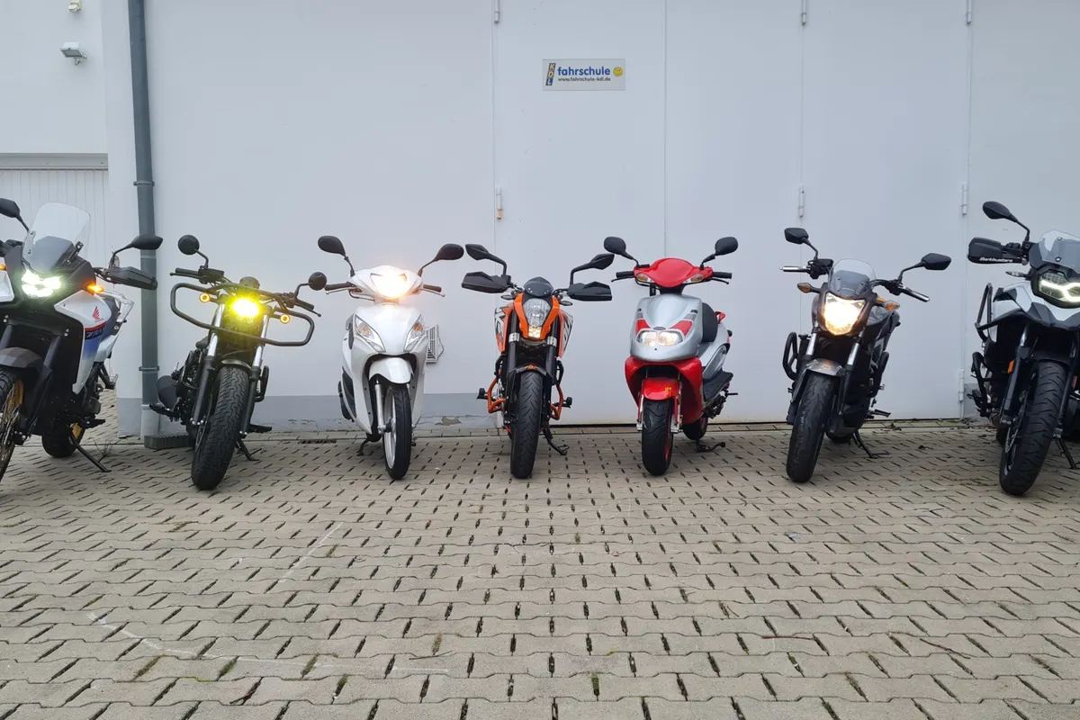 Sieben Motorräder und Roller der Fahrschule KDL in einer Reihe